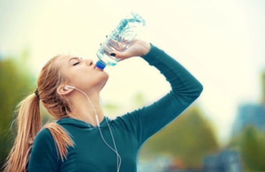 Joggerin trinkt Wasser aus PET-Flasche.