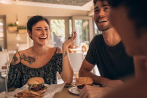 Freunde in einem Restaurant, die vergnügt Burger essen.